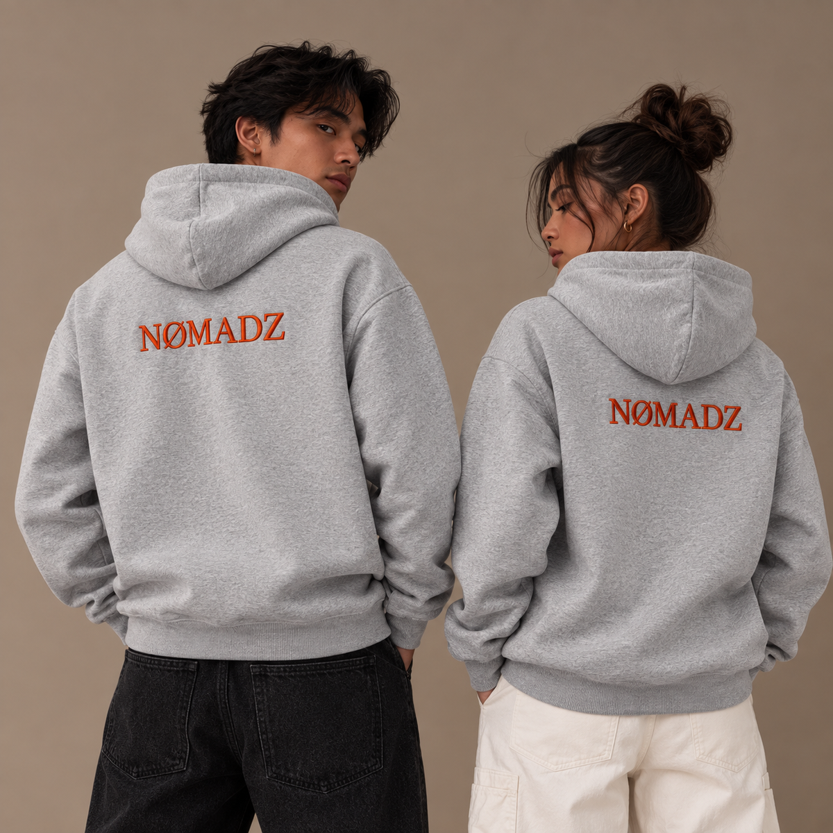 NØMADZ grey oversized hoodie with orange 3D embroidery on the back worn by male and female models