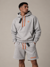 NØMADZ grey hoodie and men's shorts set with orange logo and drawstrings worn by a model