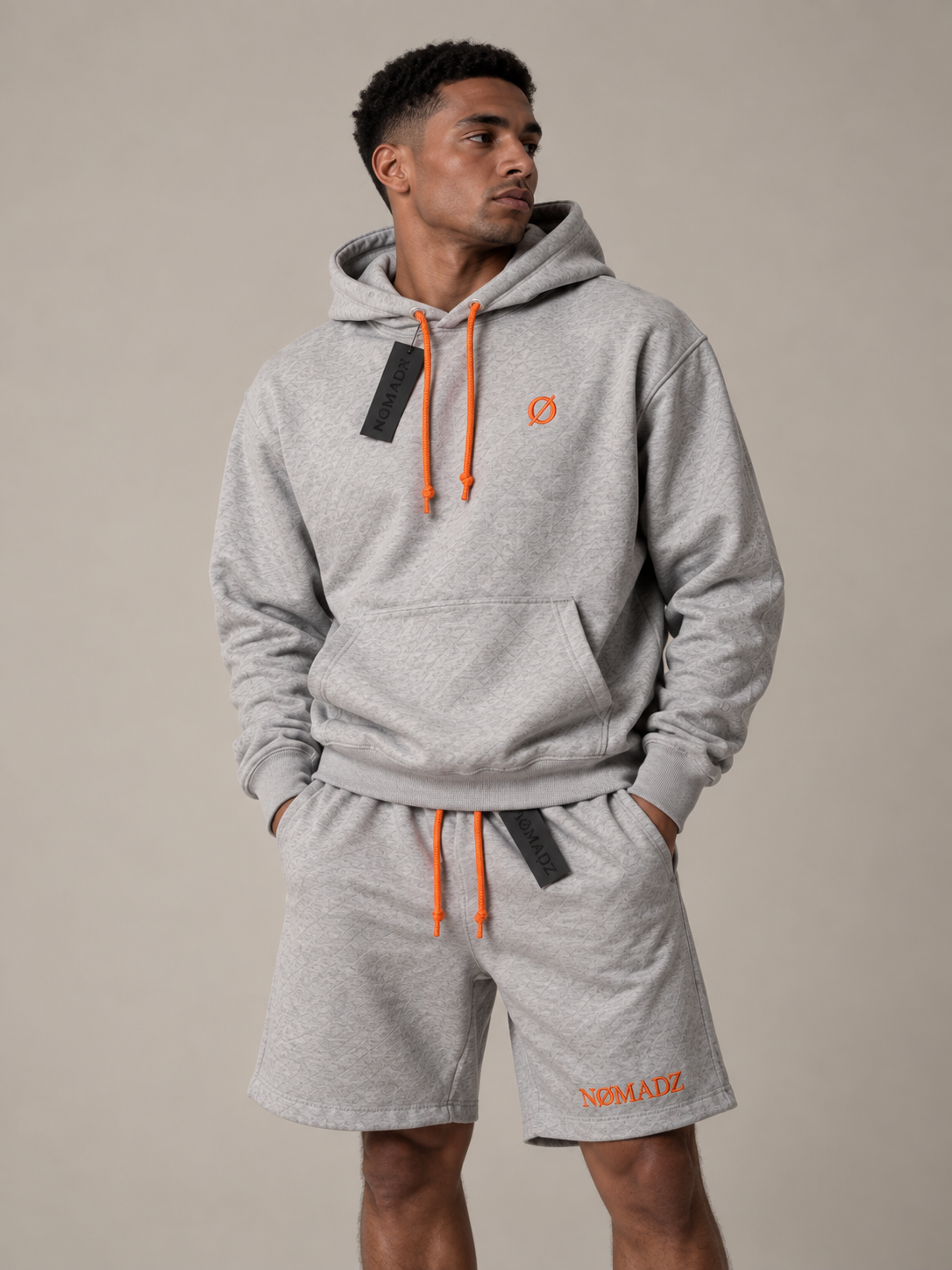 NØMADZ grey hoodie and men's shorts set with orange logo and drawstrings worn by a model