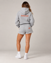 NØMADZ grey hoodie and women's shorts set with terracotta orange embroidery on the back worn by a model