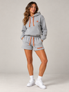 NØMADZ grey hoodie and women's shorts set with terracotta orange embroidery worn by a model