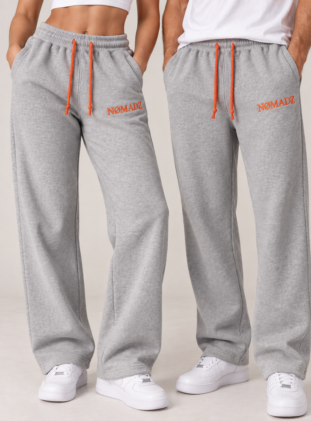 NØMADZ grey unisex joggers with orange embroidery worn by male and female models
