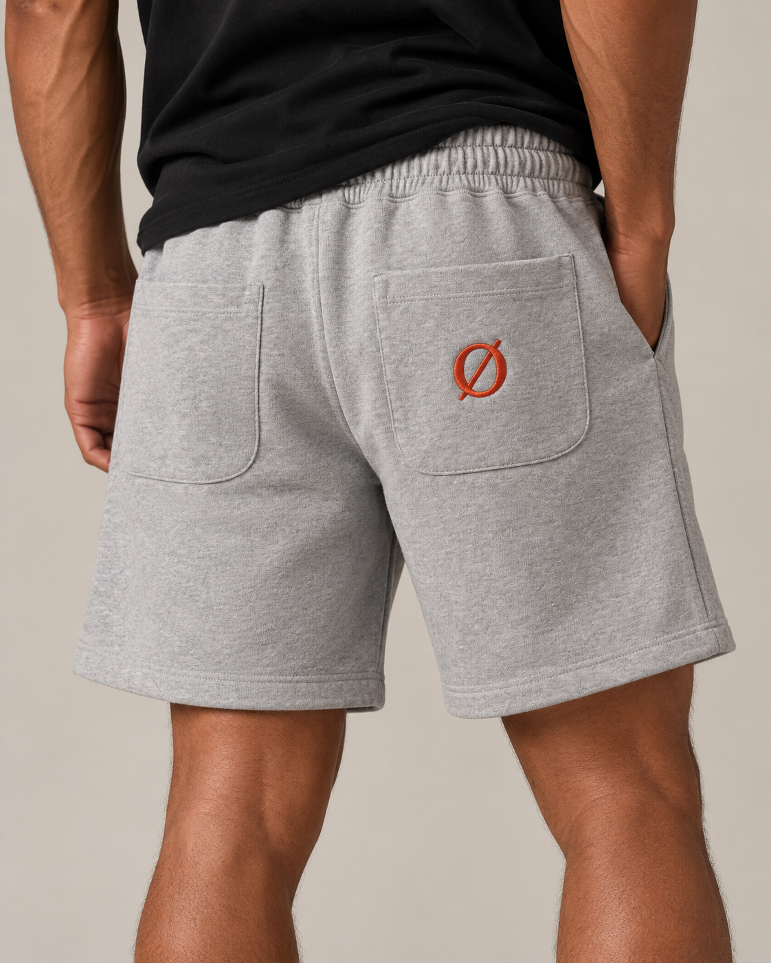 NØMADZ grey men's shorts with terracotta orange Ø embroidery on the back worn by a model