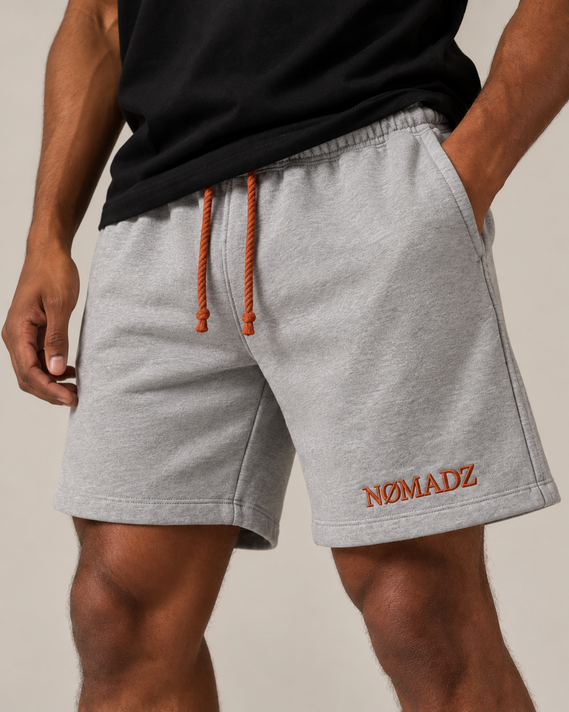 NØMADZ grey men's shorts with terracotta orange drawstring and embroidered logo worn by a model