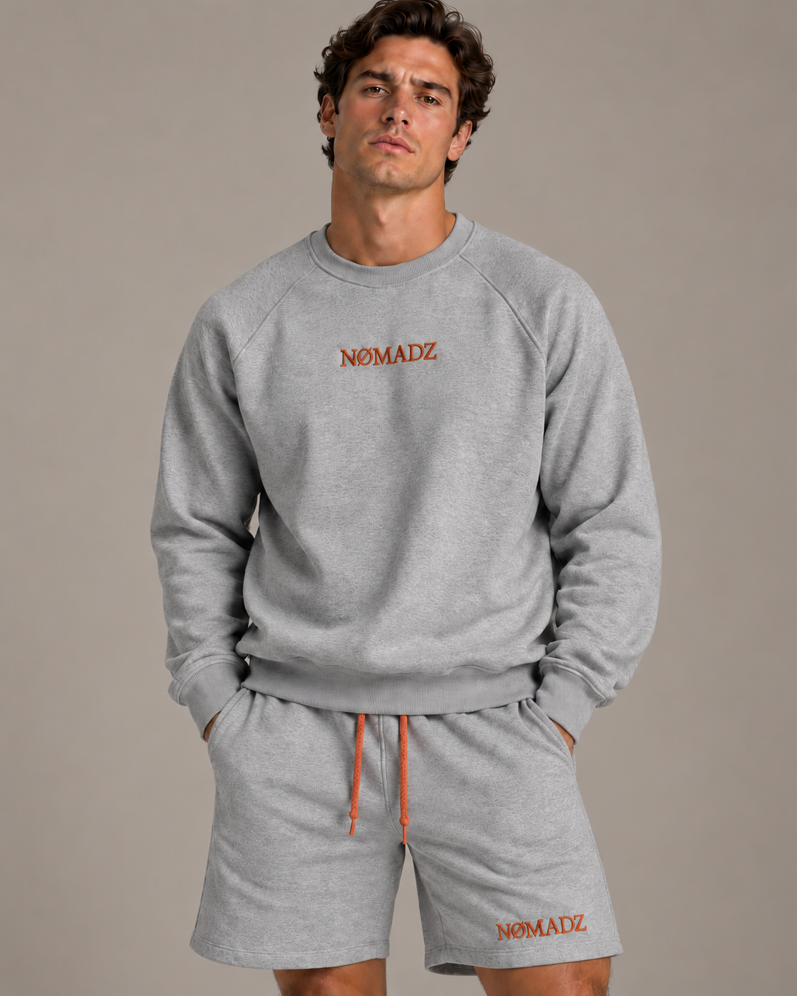 NØMADZ grey sweater and men's shorts set with orange embroidery worn by a model