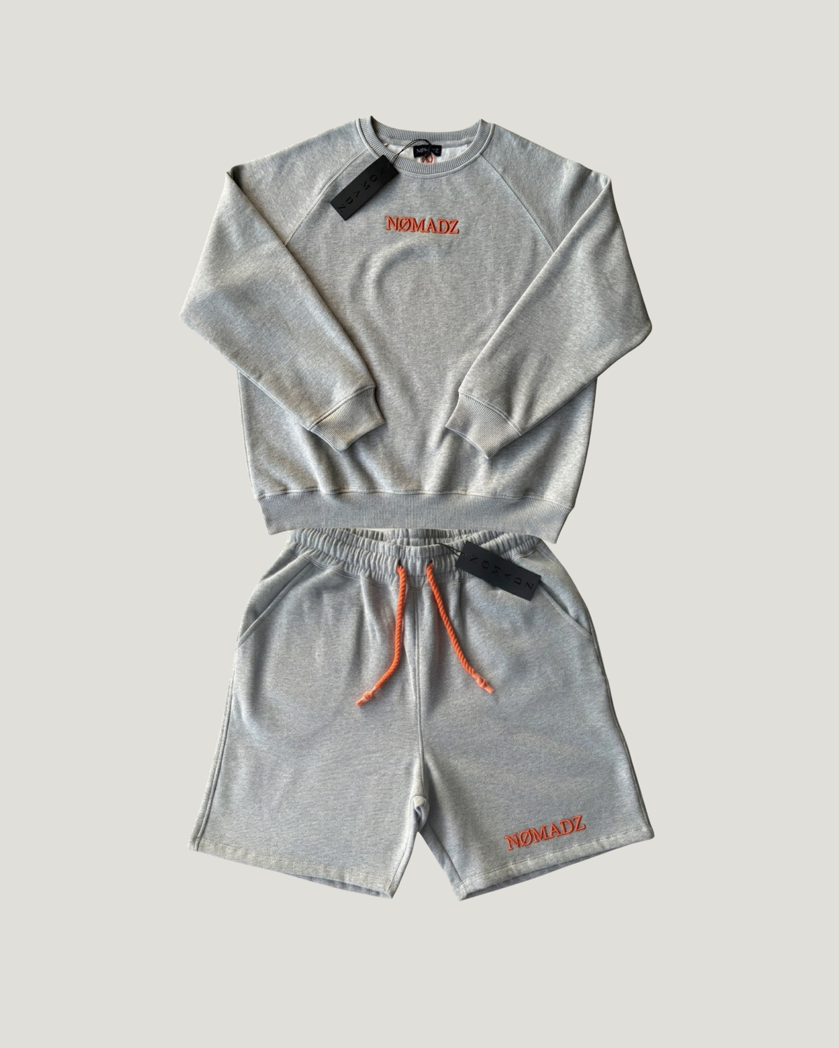 NØMADZ grey sweater and men's shorts set with orange embroidery worn by a model
