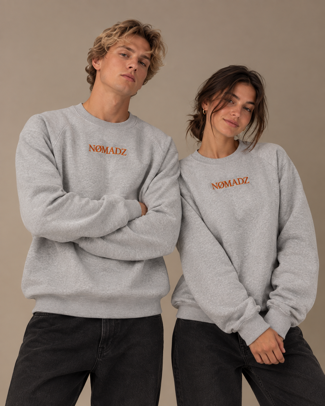 NØMADZ grey unisex sweater with burnt orange embroidered logo worn by male and female models