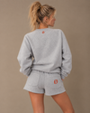 NØMADZ grey sweater and women's shorts set with orange embroidery on the back worn by a model